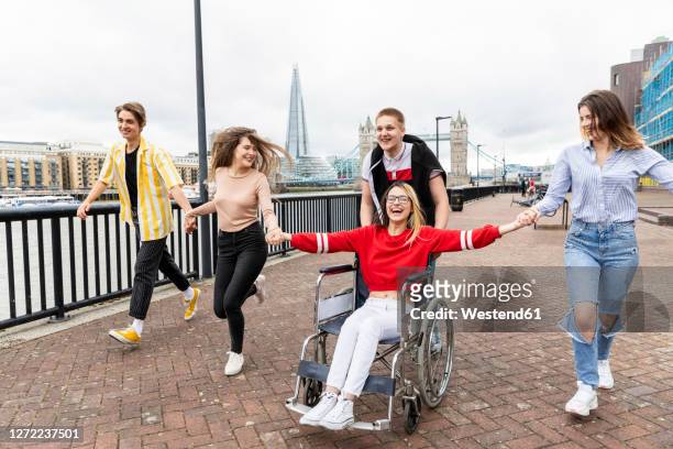 cheerful men and women with disabled female friend enjoying in city, london, uk - travel destinations running stock pictures, royalty-free photos & images