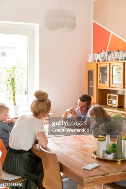 family playing board game on dining table at home during weekend - 4 people playing games stock pictures, royalty-free photos & images