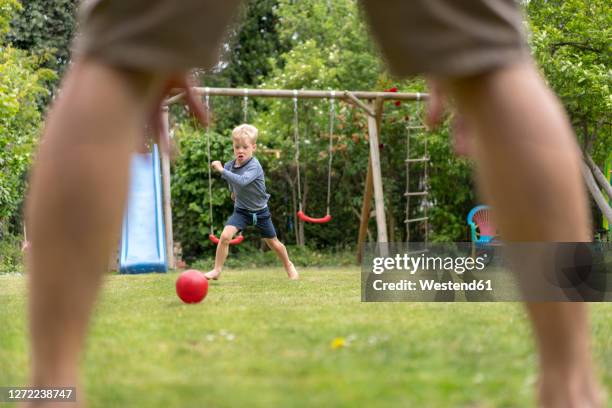 boy playing soccer with father at back yard during weekend - soccer back stock-fotos und bilder