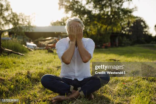 man covering face while practicing yoga in yard - covering gray hair stock pictures, royalty-free photos & images