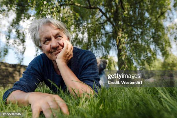 confident smiling man lying on front in field - allongé sur le devant photos et images de collection