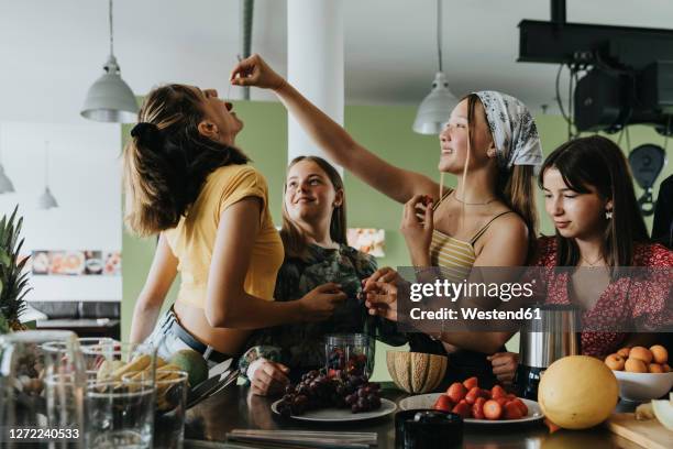teenage girls trying fresh fruit for smoothies - children fruit stock-fotos und bilder