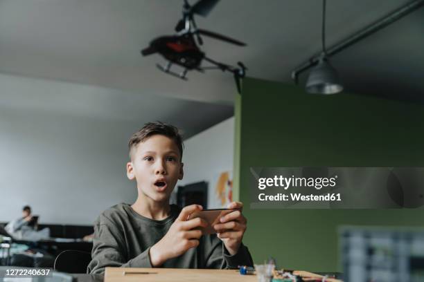 boy controlling miniature helicopter with an app - toy helicopter stock pictures, royalty-free photos & images