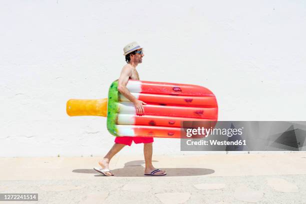 smiling man with airbed walking on sidewalk - air bed stock pictures, royalty-free photos & images