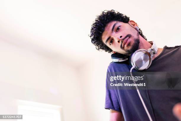 confident young male dj listening through headphones at recording studio - edm dj stock pictures, royalty-free photos & images