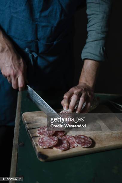 midsection of man cutting salami slices on board at table - salami stock pictures, royalty-free photos & images