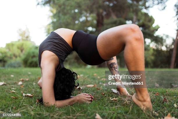 young woman practicing contortion in park - young contortionist stockfoto's en -beelden