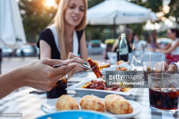happy friends having meal while sitting outdoors at cafe - tapas stock-fotos und bilder