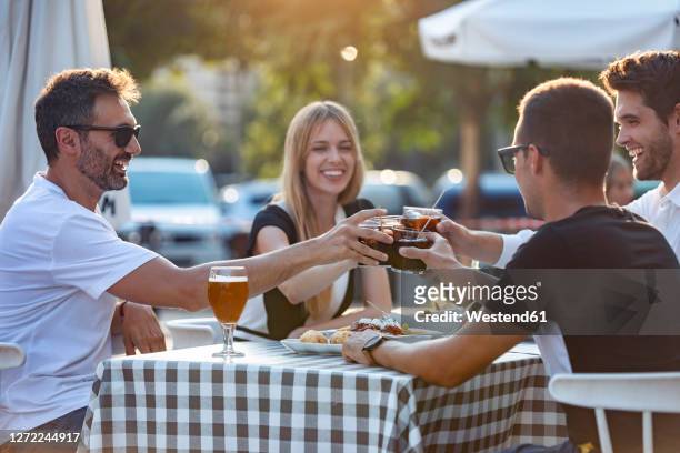 friends toasting vermouth drink while enjoying meal at cafe - cafeterias en la calle fotografías e imágenes de stock