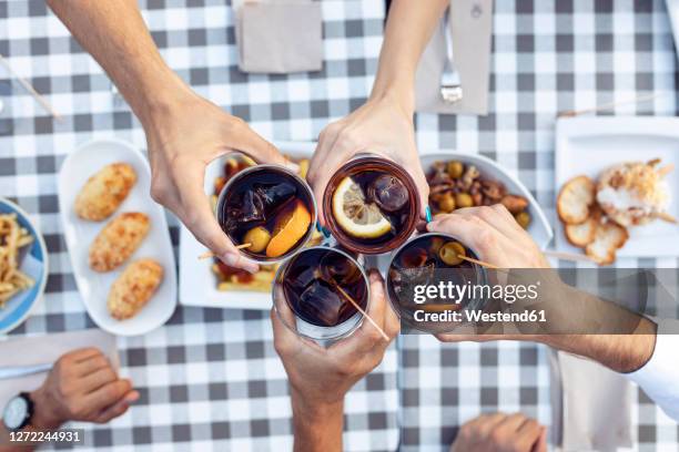 hands of friends toasting vermouth at table in cafe - vermut fotografías e imágenes de stock