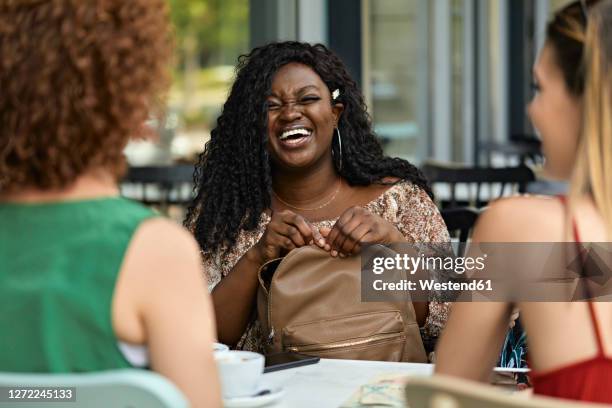 happy female friends meeting in a cafe - black purse fotografías e imágenes de stock