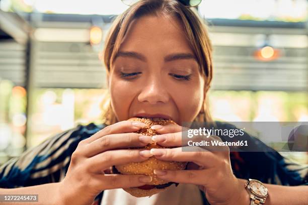 portrait of woman eating a burger - biting ストックフォトと画像