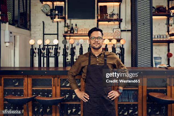 portrait of a confident waiter at the counter in a pub - bartender bildbanksfoton och bilder