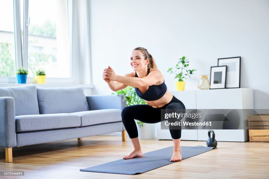 Smiling woman doing squats during home workout
