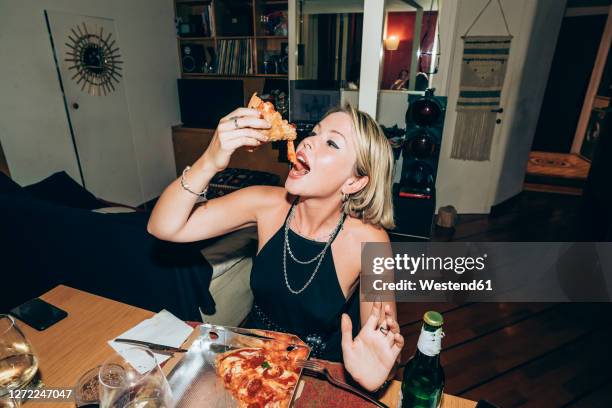 young woman enjoying pizza during party at home - pizza party stock pictures, royalty-free photos & images