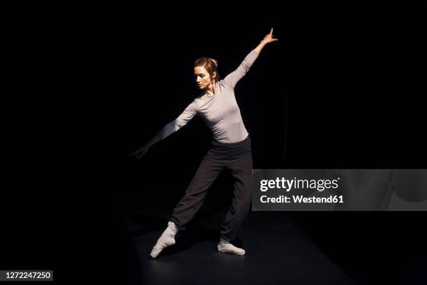 female ballet dancer rehearsing on black stage - moderner tanz stock-fotos und bilder