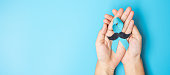 November Prostate Cancer Awareness month, adult Man holding light Blue Ribbon with mustache for supporting people living and illness. Healthcare, International men, Father and World cancer day concept