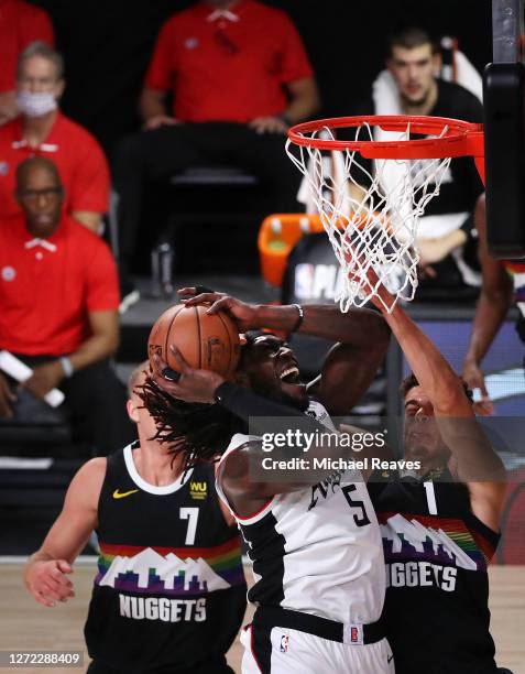 Montrezl Harrell of the LA Clippers drives to the basket over Mason Plumlee of the Denver Nuggets and Michael Porter Jr. #1 of the Denver Nuggets...