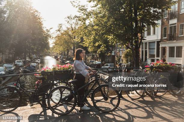 adult white woman riding bikes in amsterdam - amsterdam bike stock-fotos und bilder