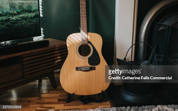 acoustic guitar in a stylish living room - acoustic guitar stock pictures, royalty-free photos & images