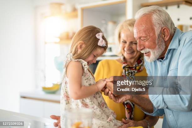 happy seniors playing with their granddaughter in the kitchen. - granddaughter stock pictures, royalty-free photos & images
