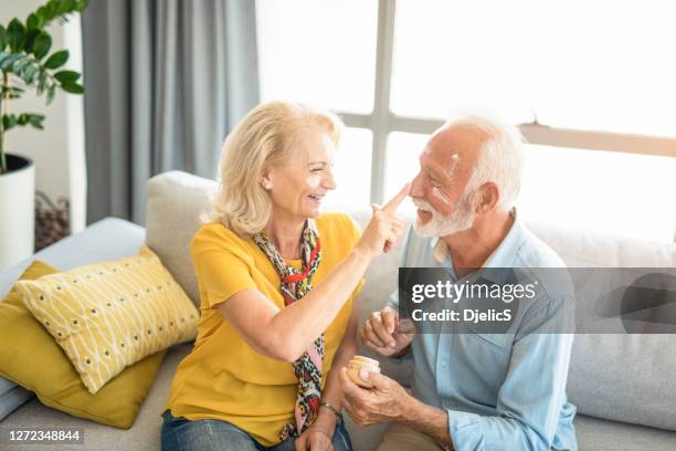 gelukkig hoger paar dat gezichtsbrandcrème toepast. - gezichtscrème stockfoto's en -beelden