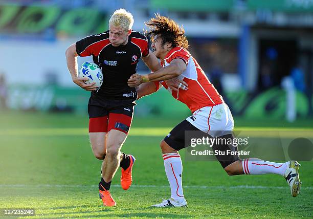 Phil MacKenzie of Canada is tackled by Kosuke Endo of Japan during the IRB 2011 Rugby World Cup Pool A match between Canada and Japan at McLean Park...