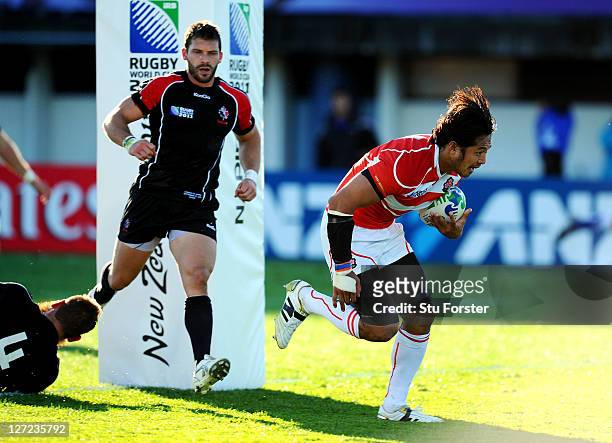 Kosuke Endo of Japan goes past the challenge from Jebb Sinclair of Canada to score his team's second try during the IRB 2011 Rugby World Cup Pool A...