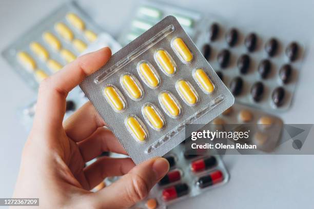 a female hand holds a package of yellow pills - blister package stock pictures, royalty-free photos & images