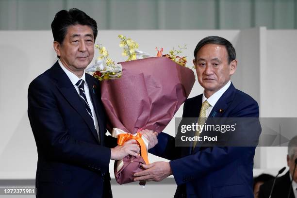 Chief Cabinet Secretary Yoshihide Suga presents flowers to Japan's Prime Minister Shinzo Abe after Suga was elected as new head of Japan��’s ruling...