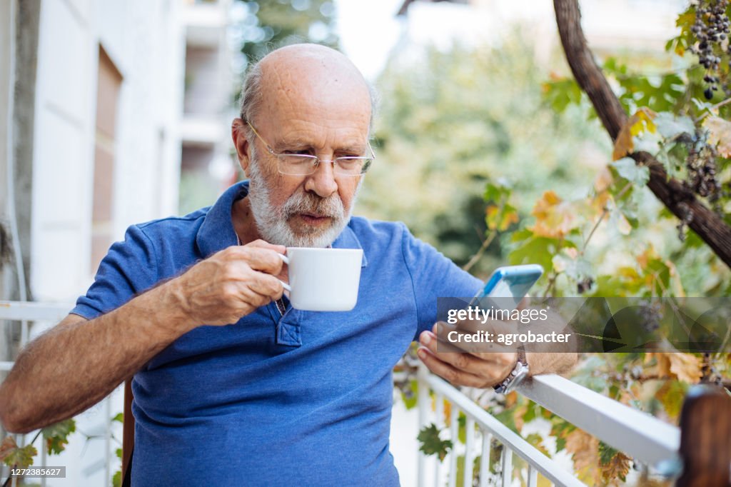 Smiling mature man enjoying in morning coffee on a terrace