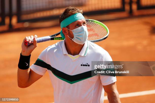 Tennys Sandgren of the United States wears a face mask as he waits for the coins toss ahead of his qualifying round match against Joao Sousa of...