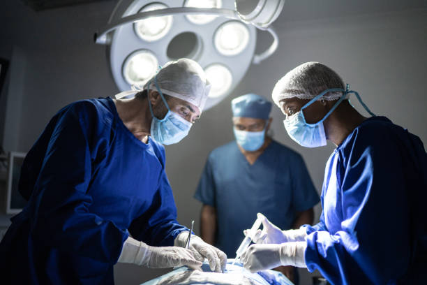 cirurgiões focados trabalhando juntos em uma cirurgia - centro cirurgico - fotografias e filmes do acervo