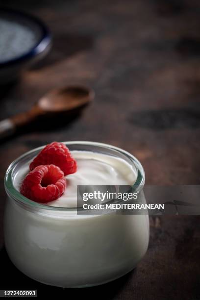 yogurt jar with rapsberries in moody low key dark wood - greek yogurt stock pictures, royalty-free photos & images