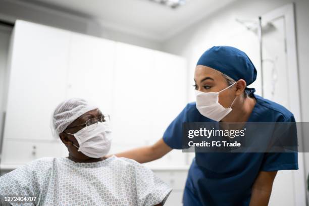 nurse talking and doing a emotional support to a female senior patient at hospital - hospital mask stock pictures, royalty-free photos & images