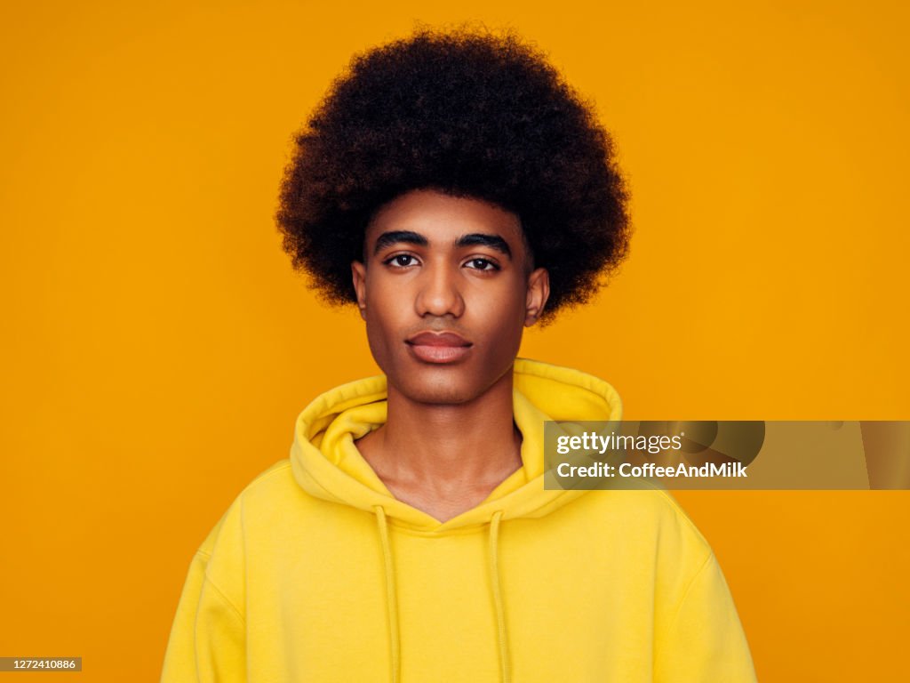 Afroamerikanischer Mann mit Afro-Haaren trägt Hoodie und steht über isoliertem gelben Hintergrund