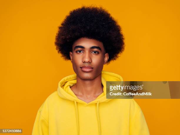 afroamerikanischer mann mit afro-haaren trägt hoodie und steht über isoliertem gelben hintergrund - afro frisur stock-fotos und bilder