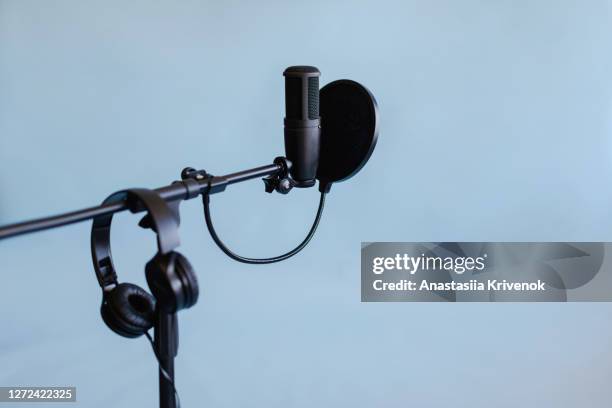 podcast streaming at studio. microphone on stand with pop filter and headphones on blue background. blogger concept. - windschutz stock-fotos und bilder