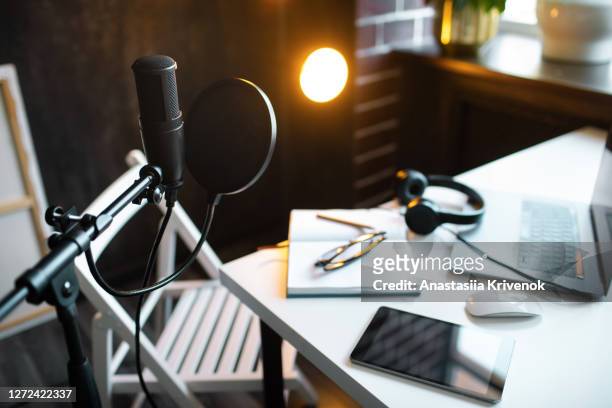 podcast streaming at home. audio studio with laptop, microphone with pop filter and headphones on white table against black wall with warm lights. blogger concept. - radio stock pictures, royalty-free photos & images