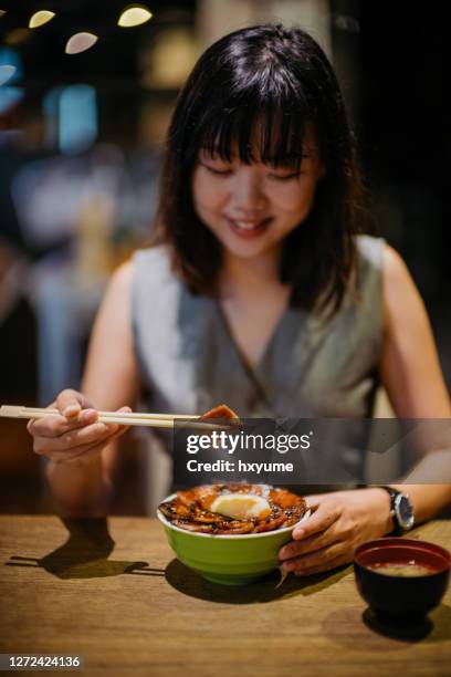 junge asiatische frau essen japanischen grill schweinereis schüssel - rice bowl stock-fotos und bilder