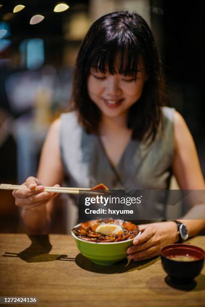 jonge aziatische vrouw die japanse kom van de grillvarkensvlees van het varkensvlees eet - rice bowl stockfoto's en -beelden