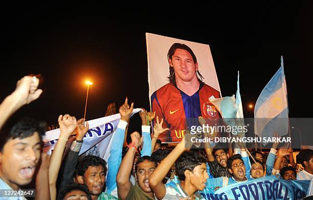 Indian fans of Argentine footballer Lionel Messi wave Argentinian and Indian national flags and hold a poster of Messi as they wait for Messi's...