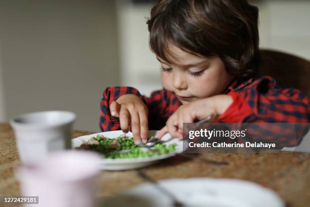 a little boy eating peas for the lunch - peas stockfoto's en -beelden