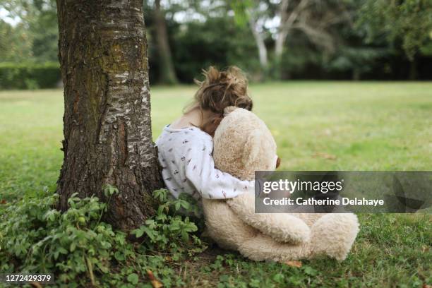 a 5 year old girl talking with her big teddy bear in the garden - chagrin photos et images de collection