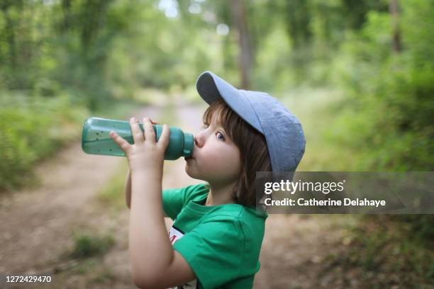 a little boy drinking water in the woods - niño-tomando-agua fotografías e imágenes de stock
