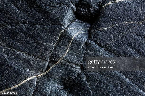 close-up of black rocks with cracks - stein stock-fotos und bilder