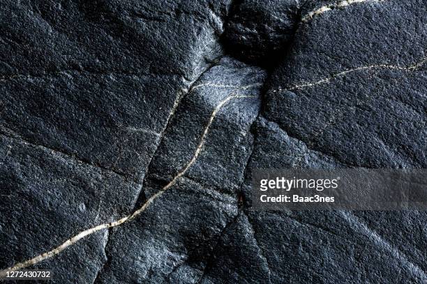 close-up of black rocks with cracks - piedra fotografías e imágenes de stock
