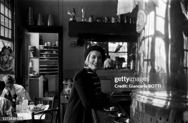 Portrait de Catherine Deneuve au comptoir d'un bistrot parisien, portant des vêtements Yves Saint-Laurent, en 1960.