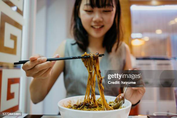 young asian woman enjoying korean chinese meal in restaurant - korean food stock pictures, royalty-free photos & images