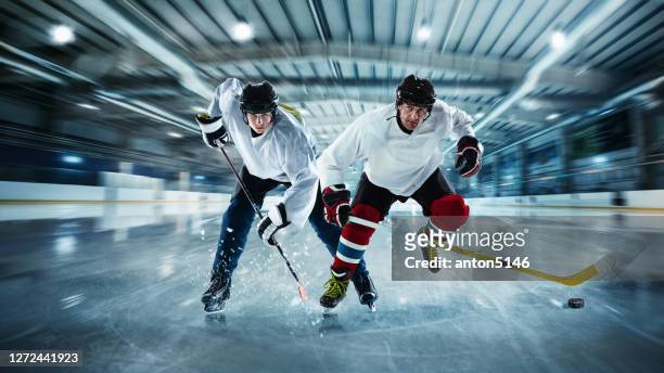 männliche hockeyspieler mit den stöcken auf dem eisplatz in bewegung und aktion - hockey player stock-fotos und bilder